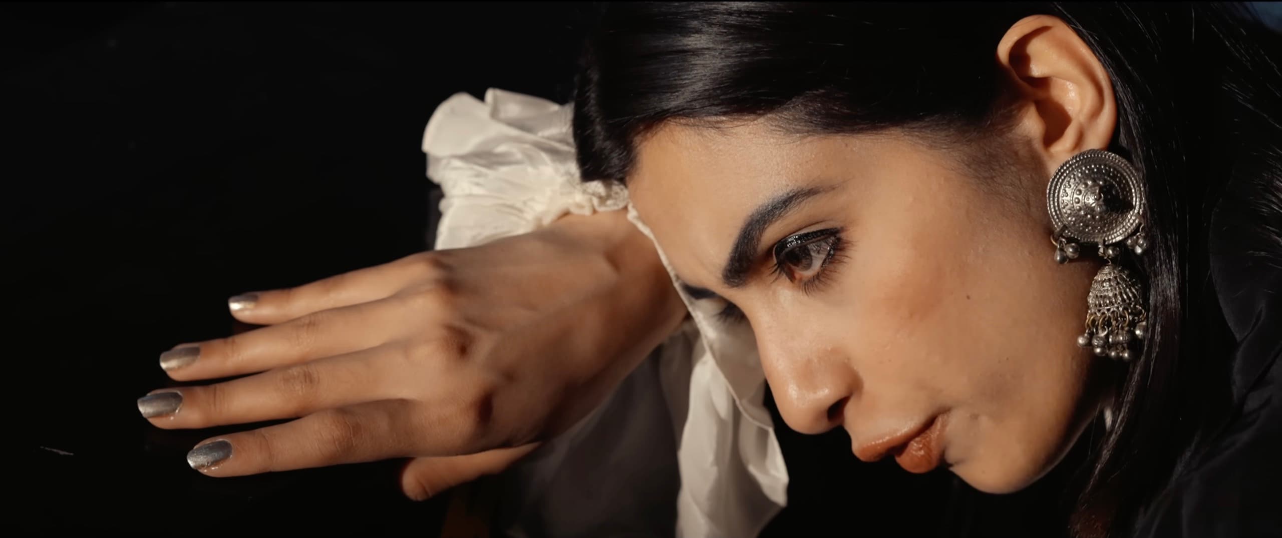 Close-up profile of Ranjani in dramatic low light with silver jewelry