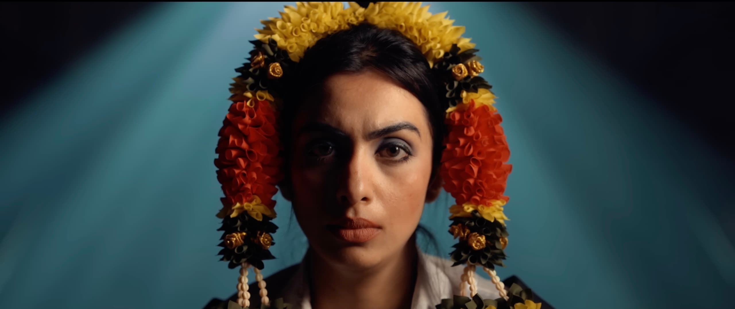 Portrait of Ranjani framed by yellow and orange flower garlands in blue light